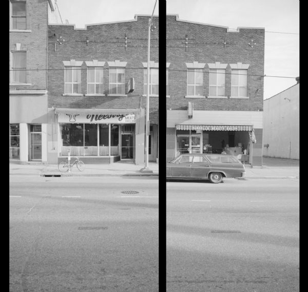 View across West Johnson Street towards Rundell's Beauty Salon (right) and Neesvig Meats (left). A car is parked along the curb, and a bicycle is parked near a parking meter on the sidewalk. The alley on the right separates the salon from Koch Motors. The building on the left is the Colonial Shoppe. 