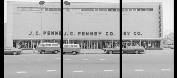 View across East Main Street at the corner of Monona Avenue (now Martin Luther King Jr Boulevard), towards the J.C. Penney Co. Mannequins displaying clothing are on display in the windows on both sides of the main entrance. Pedestrians are walking on the sidewalk, and two cars and a Volkswagen van are parked along the curb in front of the building.