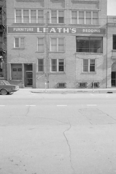 View across North Fairchild Street towards the back side of the Haswell Building. The building houses Leath's Furniture Store, and there is a loading dock on the left near a rear entrance door.