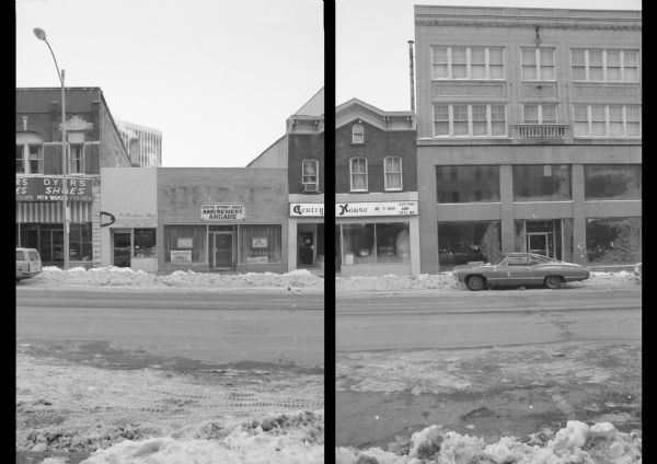 View across State Street towards several buildings on the 100 block. On the far left next to Dyers Shoes is Collector's Shop Stamps and Coins. The next building is State Street Adult Amusement Arcade. The Fred Huels Building contains Gentry House, a men's hair salon. The Haswell Building contains Leath's Furniture. A sign on the left hand ground floor window of Leath's is behind a parked car and reads: "For Lease." 