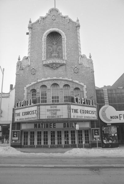 View across State Street towards the Capitol Theater, designed in a Spanish colonial style and highly decorative, including arched windows above the marquee. The marquee advertises that the theater is showing The Exorcist.