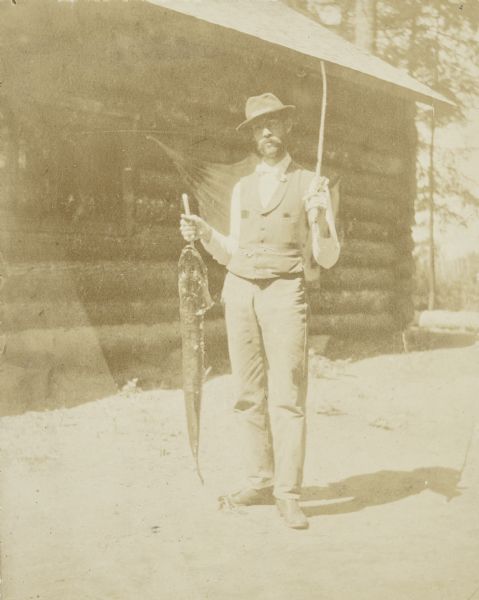 Grant Stroh posing with a big pickerel in front of Island Lodge. Caption reads: "Pickerel from Little Horn Lake 39 inches — Grant Stroh."
