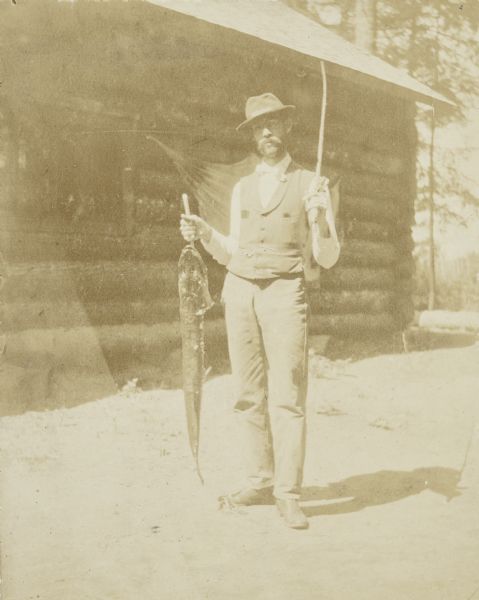 Grant Stroh posing with a big pickerel in front of Island Lodge. Caption reads: "Pickerel from Little Horn Lake 39 inches — Grant Stroh." 