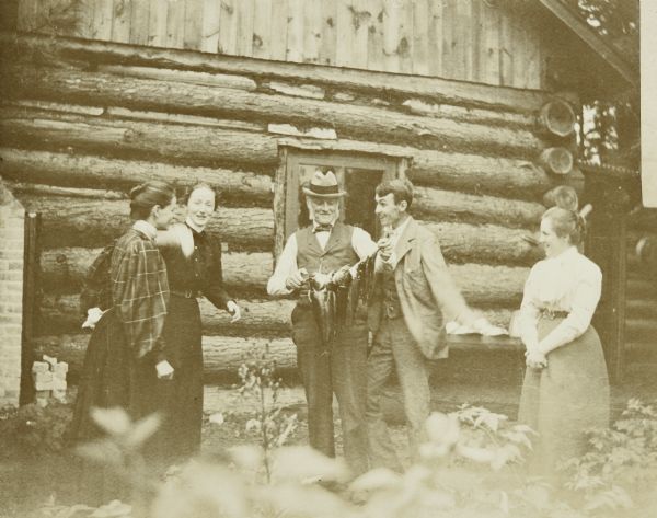 W.A. Holt is showing off the perch he caught. Names from left to right are: Lucy Holt, Minnie May Rumsey, I.P. Rumsey, W.A. Holt and Bertha {unknown}. Caption reads: "Now — look enthusiastic!" Initials and names written below the photograph are, from left to right: "LRH, MMR, IPR, WAH, Bertha."