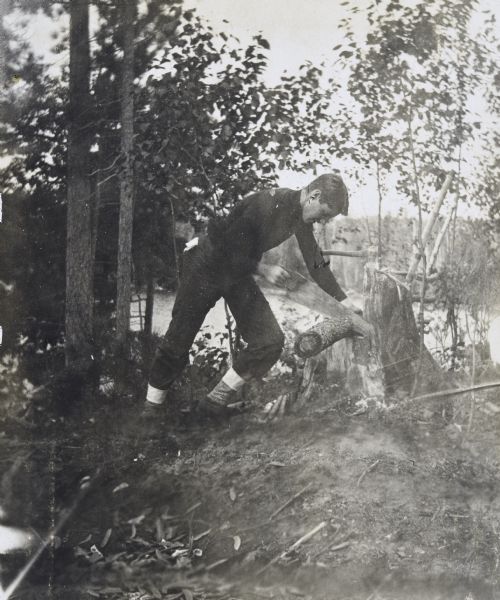 Wallace Rumsey is building a wooden seat from a fallen log at Lookout Point on the Island at Archibald Lake. Caption reads: "Building the seat on the point — WDR."