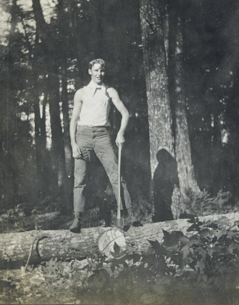 With ax in hand, Wallace Rumsey is standing on a gigantic fallen tree. Caption reads: "Wallace — Chopper."