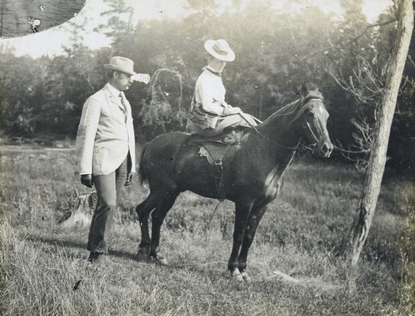 Anna Holt Wheeler riding sidesaddle on the horse named Dick, with her husband Arthur Dana Wheeler walking behind her. Caption reads: "Mr. and Mrs. Wheeler and Dick." 