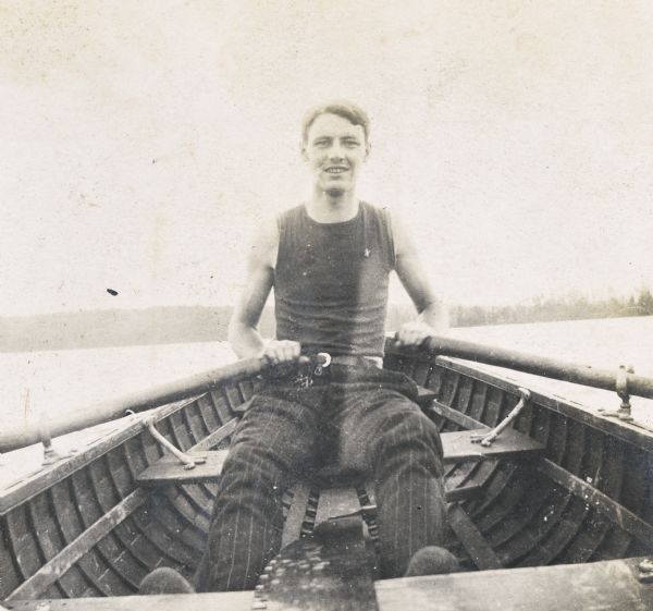 A close-up of Wallace Rumsey rowing on Archibald Lake. Photo album page heading reads: "The recreations of Uncle Wallace."