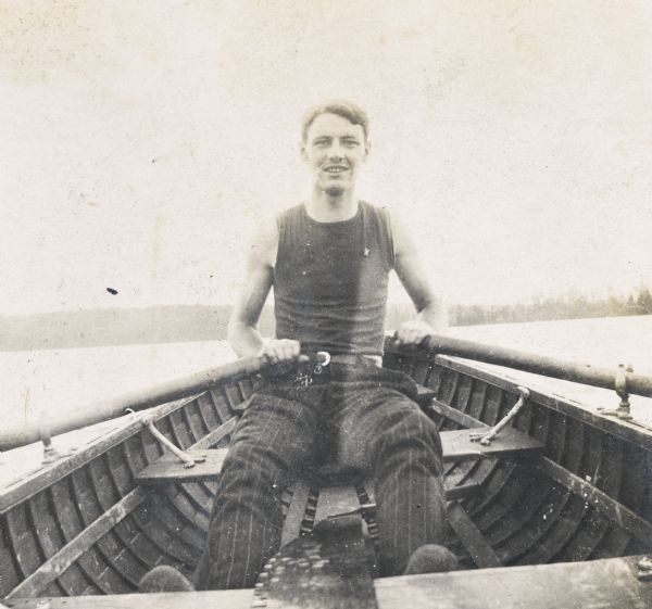 A close-up of Wallace Rumsey rowing on Archibald Lake. Photo album page heading reads: "The recreations of Uncle Wallace." 