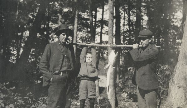 At Maiden Lake, Dr. Hoover (left) and Rev. John Robertson Macartney (right) are holding a pole with a large pickeral, the size of a boy, hanging from it. Page heading reads: "Rev. J. Robertson Macartney, Pickeral, Maiden Lake 1903." Caption below reads: "Dr. Hoover."