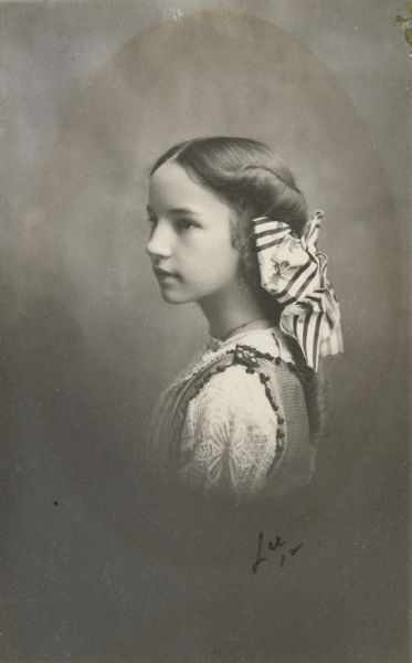 Quarter-length studio portrait of Mary Eleanor Holt in semi-profile. She has a large, striped bow in her hair.

