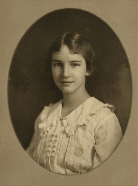 Oval-framed quarter-length studio portrait of Mary Eleanor Holt. She is wearing a shirt or dress with a ruffled collar. Her hair is parted in the center. Caption reads: "Eleanor."
