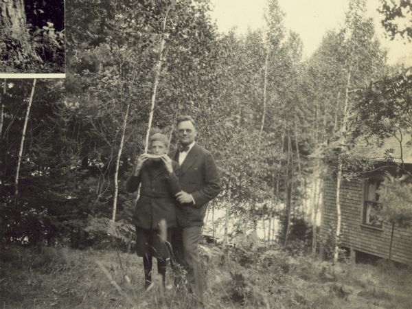 Freddy is biting into a slice of watermelon with Dr. McDaniels next to him. Archibald Lake, tall trees, and a cabin are in the background. Page title reads "Archibald Lake, August 1923." Caption reads "Dr. McDaniels and Freddy, August 9, 1923."
