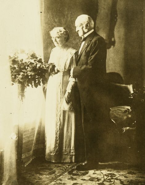 Wearing formal attire, Captain I.P. Rumsey and Mary Axtell Rumsey are standing together by a window. Caption reads: "50th Anniversary."