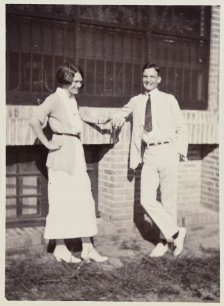 Teachers Alfred Holt and Madeleine Wood Holt are standing together in front of a building, possibly in Guangdong (Canton), China.
