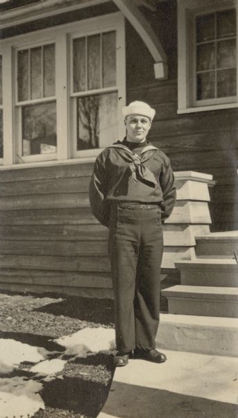 Dressed in his U.S. Navy uniform, Clinton DeWitt is posing for a portrait in front of a house. Caption reads: "Clinton DeWitt."