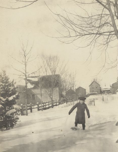 Alfred Holt is snowshoeing in the backyard of the Holt family home in Oconto. A wood fence and neighboring homes are in the background. Caption reads: "Alfred Snowshoing." Page caption reads: "Thanksgiving 1903. Oconto."