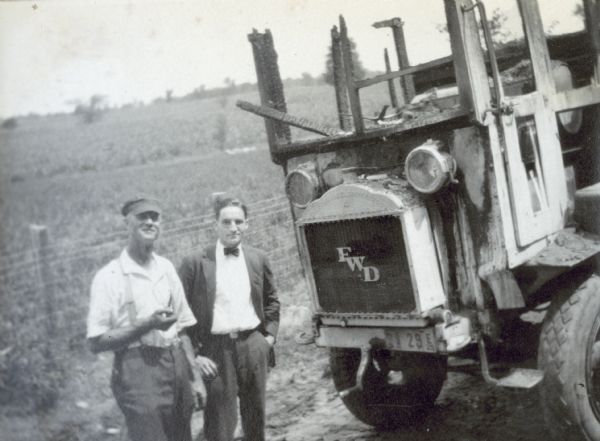 Donald Holt and another man are standing by the truck which caught fire while moving items to Island Lodge. The initials "FWD" are on the grill of the truck. Caption reads: "Truck Caught Fire on August 8, moving to I.L."