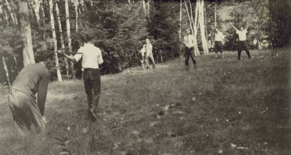 W.A. Holt is the pitcher in this baseball game. The batter is Henry Nubigan. At third base is Alfred Holt and {Unknown}. In the outfield from L to R is: {Unknown} and Donald Holt. There are tall trees in the background.
