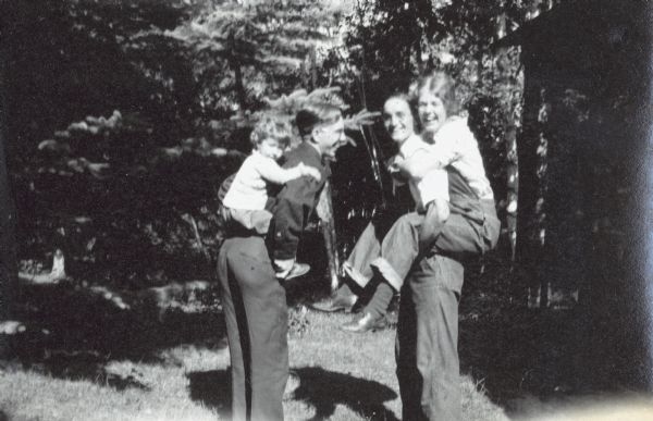 On the left, little Betty Ann is getting a piggyback ride from Clarence Showalter. In contrast, on the right, big Lillian Wheeler is getting a piggyback ride from Don Holt. Caption reads: "Clarence and Betty Ann, Don and Lillian."