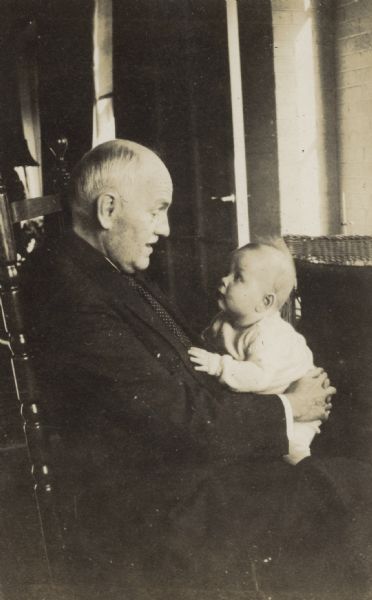 Baby William Arthur Rumsey is sitting in the lap of an unknown man, possibly a relative. The two are making eye contact. Caption reads: "William Arthur Rumsey."