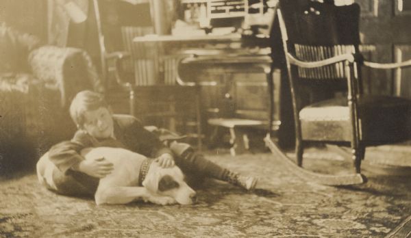 On the carpeted floor, David Rumsey is leaning on Spotty the dog, possibly in the home of Lucy and W.A. Holt.
