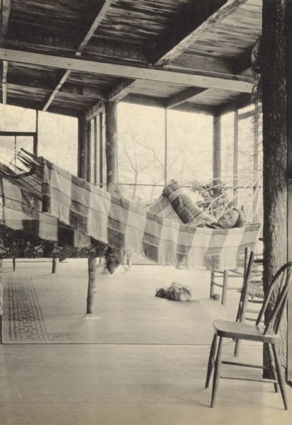 A woman is napping in the hammock on the screened porch at Island Lodge. Her bag and possibly a camera are on the floor near her. Caption reads: "July 30 - Aug 8."