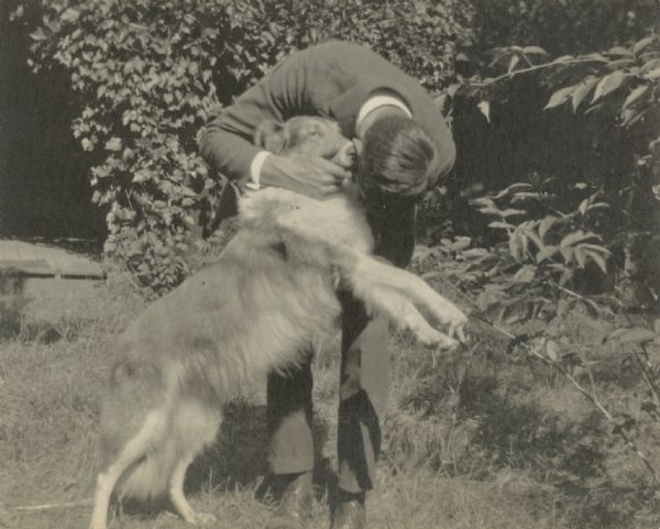 A Collie named Queenie, the Wheeler's dog, appears to be whispering in Gordon Wheeler's ear.