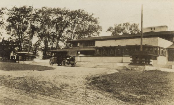 Exterior view of the Lake Geneva Hotel, a two-story, low horizontal building. A man is standing next to the car parked in front of the hotel. Caption reads: "Lake Geneva."