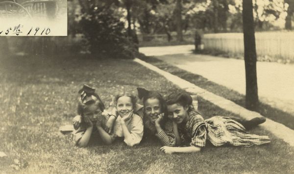 Looking at the camera, Eleanor Holt and three girlfriends are lying on their stomachs in a yard. Caption reads: "Margaret Doran, Eleanor H, Kathlene Doran, Marion Doran."