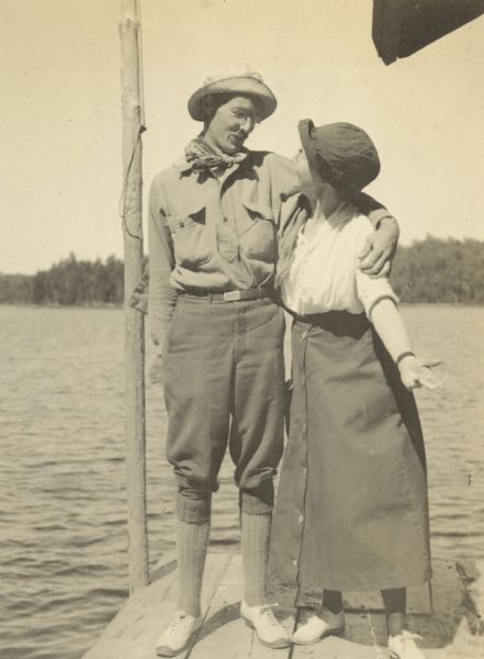 A man and woman are striking a theatrical pose on the pier. Lake Michigamme is in the background.