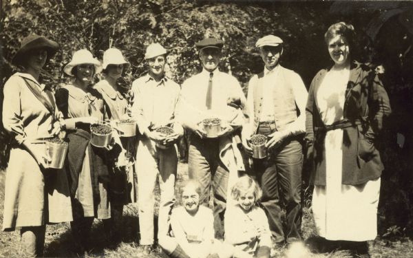 A group of Holts and Garrisons are showing their berry harvest. Names from left to right: Unknown, Eleanor Holt, Jeannette Holt, Donald Holt, Mr. Garrison, W.A. Holt, Mrs. Garrison, and unknown children.