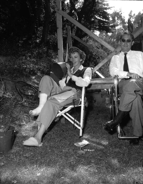 Director Ida Lupino sitting next to unknown man while making the 1949 film "Never Fear." She is speaking into a megaphone and has papers, most likely a script, in her lap.