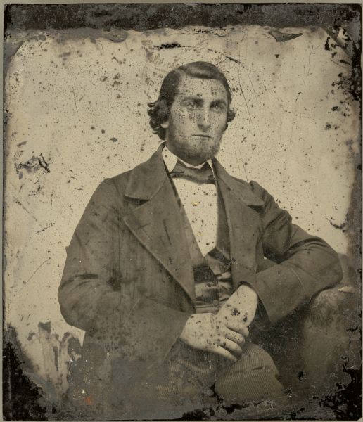 A seated, three-quarter ambrotype portrait of George Brumder (1839-1910) wearing a suit, vest and necktie.  He has a beard but no mustache. His shirt studs have been highlighted with gold applied to the surface of the photograph.