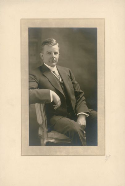 A three-quarter length seated portrait of Herman Otto Brumder (1880-1950). He is wearing a three piece suit, tie, and high collar. A son of publisher George Brumder (1839-1910), H.O. Brumder was president of the Pressed Steel Tank Company of West Allis.