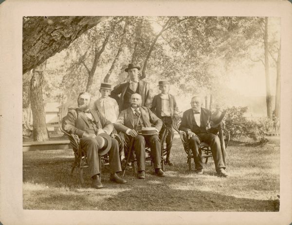 An outdoor group portrait of George Brumder, sitting in a bent willow chair at far left; Dr. Herman Duemling, sitting in the center, and Julius Andrae, sitting on the far right. Duemling worked with Brumder as an editor at Germania Publishing and was also active in Grace Lutheran Church. Andrae, described on the back of the photograph as a "lifelong friend of Geo. Brumder," was the founder of a telephone and electrical equipment manufacturing company. Standing behind the men are three sons of George Brumder, from left: Herman Otto, Alfred Julius, and George Frederick Brumder.  
