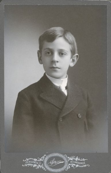 Waist-up studio portrait of Herbert Paul Brumder (1885-1967), the youngest child of George and Henriette Brandhorst Brumder. He is wearing a double breasted suit coat, necktie and high collared shirt.  