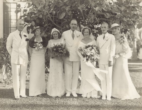 Outdoor group portrait of William George Brumder, center, and his bride June Johnston on their wedding day in Florida. Pictured with them, from left, are June's parents, Walter Vail and Bessie "June" Johnston; June's sister, Patsy Johnston; the wedding couple; William's brother, Robert Charles Brumder, and William's mother Thekla Uihlein Brumder. William's father, William Charles Brumder, was deceased.  