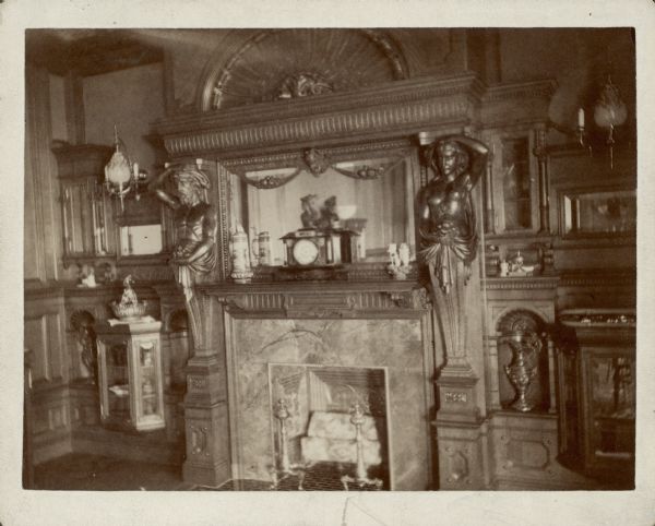 An atlas, left, and caryatid flank the fireplace in the dining room of the George Brumder residence at the corner of Grand (later Wisconsin) Avenue and 18th Street. Carved wood paneling with shelves and niches covers the wall. There are sconces fitted for both gas and electricity.
