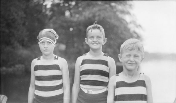 The three children of Herbert P. and Margaret Bouer Brumder are smiling while posing in their swimsuits near Pine Lake. They are, from left, Barbara, Herbert E. and Philip G. Brumder. Barbara is wearing a swim cap.