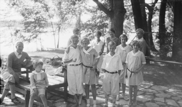 Members of the Brumder family posing on a flagstone patio near the Herbert P. Brumder summer house on Pine Lake. Sitting at the picnic table are Clifford F. Messinger and his son Clifford F. Messinger Jr. The children standing beside the table are, from left, Herbert E. Brumder, Barbara Brumder, Philip Brumder, Mary Messinger, and Joanne Messinger. The women in the background are, unidentified, Margaret Bouer Brumder, Gertrude Merker Messinger, and Ida Brumder Merker.