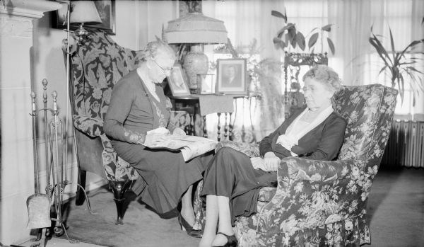 Two well-dressed women, possibly Amelia Brumder Mayer, left, and Ida Brumder Merker, right, sitting in easy chairs in the home of their younger brother, Herbert P. Brumder, at 2030 East Lafayette Place.