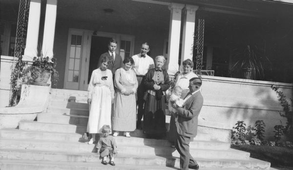 Herman Otto Brumder, lower right, holding his niece, Barbara Brumder, at the foot of the front steps at Villa Henrietta, the summer home on Pine Lake built by Milwaukee publisher and businessman George Brumder and his wife Henriette. Barbara's older brother Herbert E. Brumder is sitting on a step in front of his mother, Margaret Bouer (Mrs. Herbert P.) Brumder. The other three women are, from left, Myrtle Edwards (Mrs. Herman) Brumder, Henriette Brumder, and Ida Brumder Merker. Clifford Messinger, wearing a bow tie, is standing on an upper step. (Clifford was married to Ida's daughter Gertrude.) The young man at top left is George Gustave Brumder.