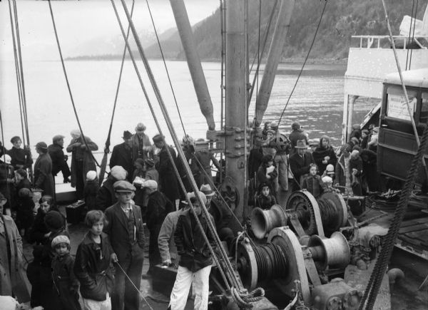 Elevated view of men, women and children ready to disembark ship. Original caption reads: "Determination to make good is written on the faces of the Wisconsin pioneers shown on board the St. Mihiel in the harbor at Seward as they wait for the ship to dock."