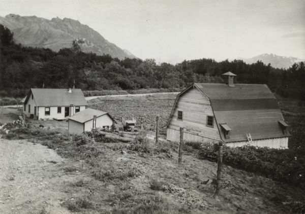 Elevated view of the farm. Original caption reads, in part: "A loud wail? is arising from the Matanuska Valley of Alaska colonists because the government is reducing their credit allowance but the community continues to grow." "Set snugly on a hillside is the farm of Walter Pippel, called the No. 1 colonist because he grew $5,000 worth of products last season."