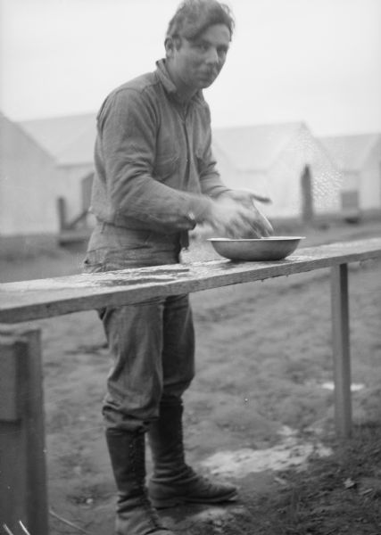 One of two images under the headline: "Trials of Pioneers Bring Families Closer Together." Original caption reads, in part: "... at the right is a colonist washing his hands in a basin of water warmed by a wood fire."