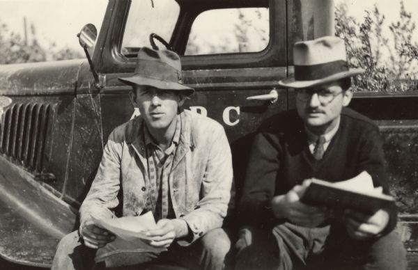 Original caption reads: "Stewart Campbell (left) and John Givens, VIPs in Matanuska Colony administration. Campbell was property manager; Givens an architect who subsequently was colony manager several times." Caption with negative reads: "Stewart Campbell, property custodian on colony project, and John Givens, warehouse clerk. Both came to Palmer from Washington, D.C. Their clothes show how officials and everybody are roughing it on this project."