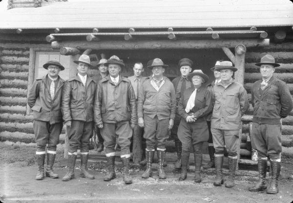 Original caption reads: "S.R. Fuller, Jr., and his party pose in front of the construction division's log office. Maybe this will yield a half-col head or two sometime. Front row, left to right: Dr. J.R. Murdock, Daniel E. McGrath, Dr. R.G. Davis, Capt. Charles Parsons of the navy, Mrs. S.R. Fuller, Jr., S.R. Fuller, Jr., Lt. Col. L.P. Hunt. Rear row, left to right: David Williams, H.W. Scott, A.M. Goodman, Lieut. H.V. Martin, and H.B. Hommon."