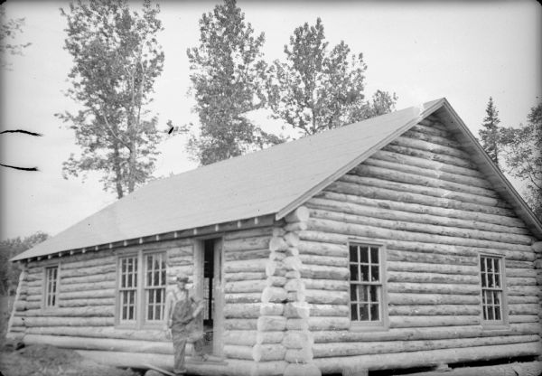 Original caption reads: "Joe Puhl of Rice Lake, Wis., and several colonist neighbors banded together to build their own cottages. They finished Puhl's first, the first in the first in the project erected exclusively by colonists. Puhl is shown at his front door."