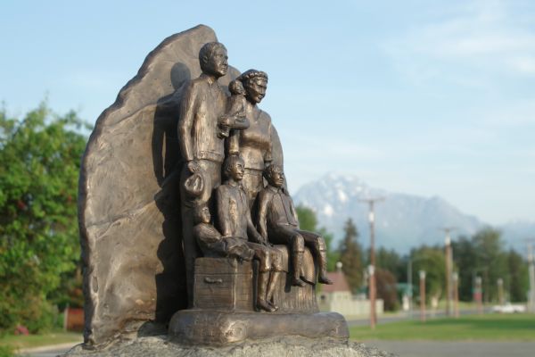 Palmer tribute statue outdoors. The statue is based on the 1935 color photograph of the George and Edith Conners family. Mountains are in the distance.